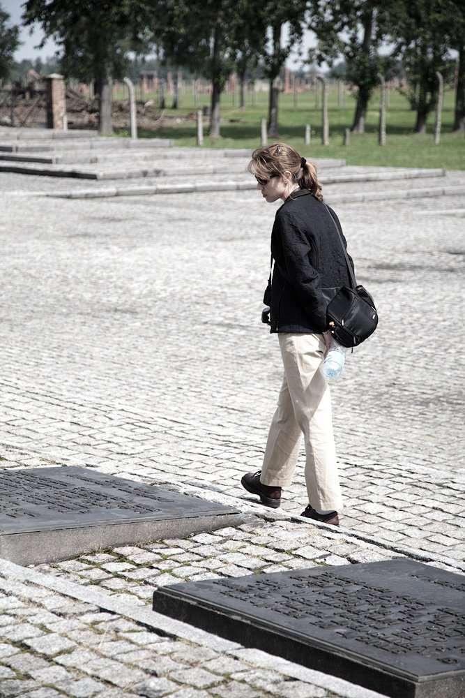 Kristie is strolling along a cobblestone walkway surrounded by historic stone monuments and lush greenery.