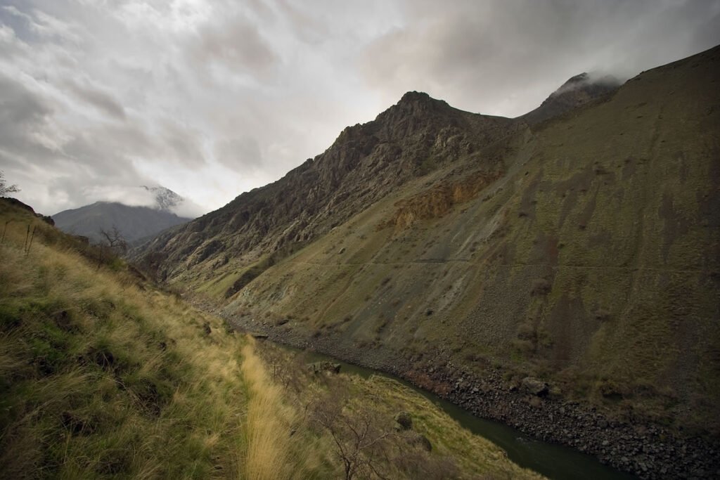 A misty mountain valley with steep slopes and a winding path, creating a moody and reflective atmosphere.