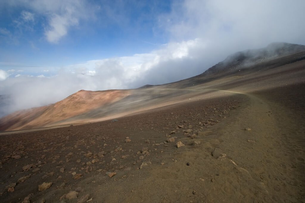 A serene mountain landscape shrouded in mist with a clear blue sky above.