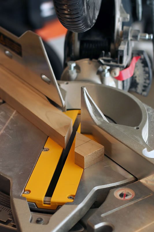 Close-up of a yellow and silver miter saw making a precise cut on a piece of wood.
