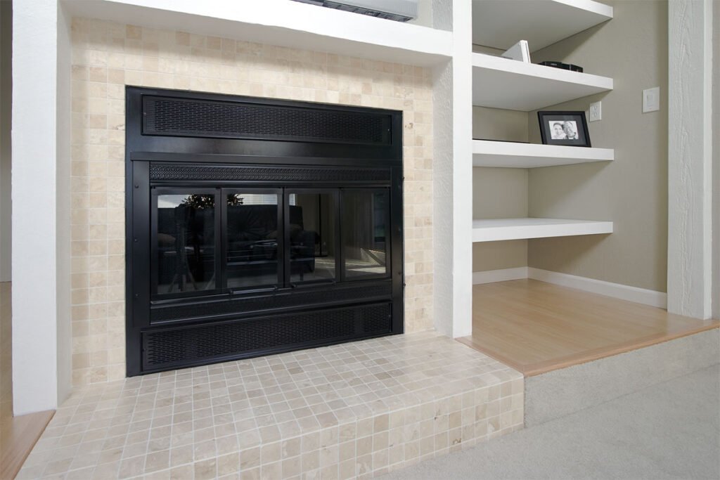 A cozy living space featuring a sleek black fireplace flanked by elegant white built-in shelves. The scene is complemented by warm wood flooring and soft carpeting.