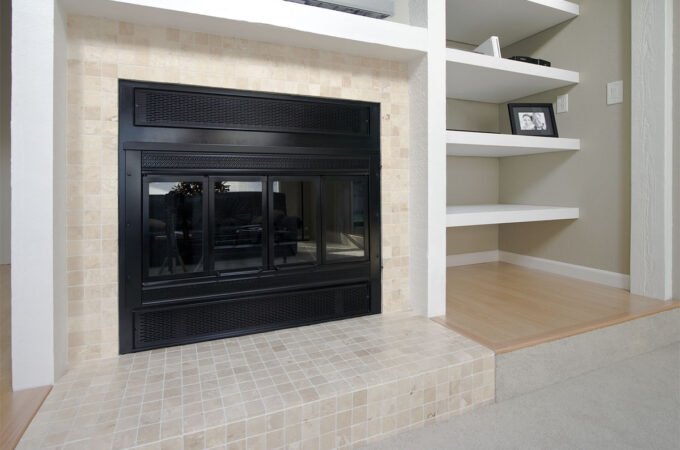 A cozy living space featuring a sleek black fireplace flanked by elegant white built-in shelves. The scene is complemented by warm wood flooring and soft carpeting.