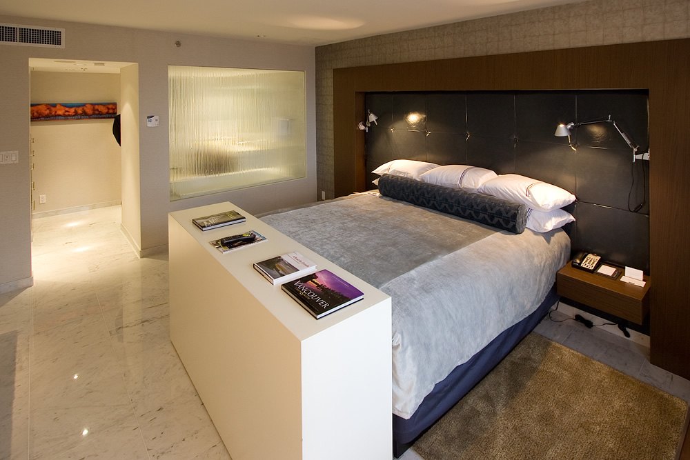 A modern hotel room featuring a cozy bed, sleek lighting, and a stylish wardrobe area.