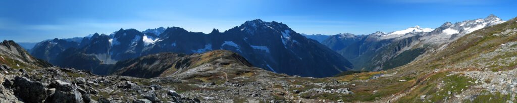A panoramic view of majestic mountains and rocky terrain under a clear blue sky, showcasing the beauty of nature.