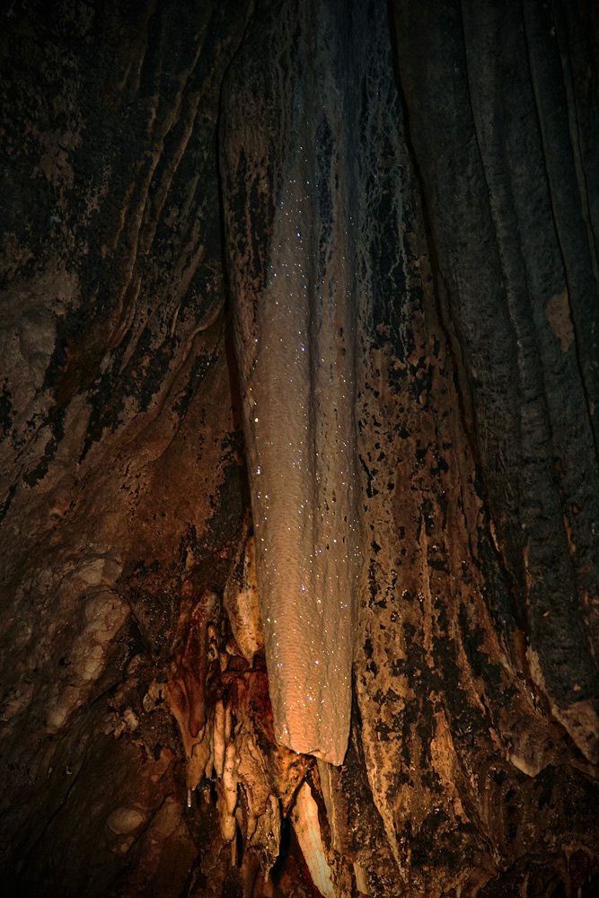 A dimly lit cave interior with warm light highlighting textures of the rock walls.