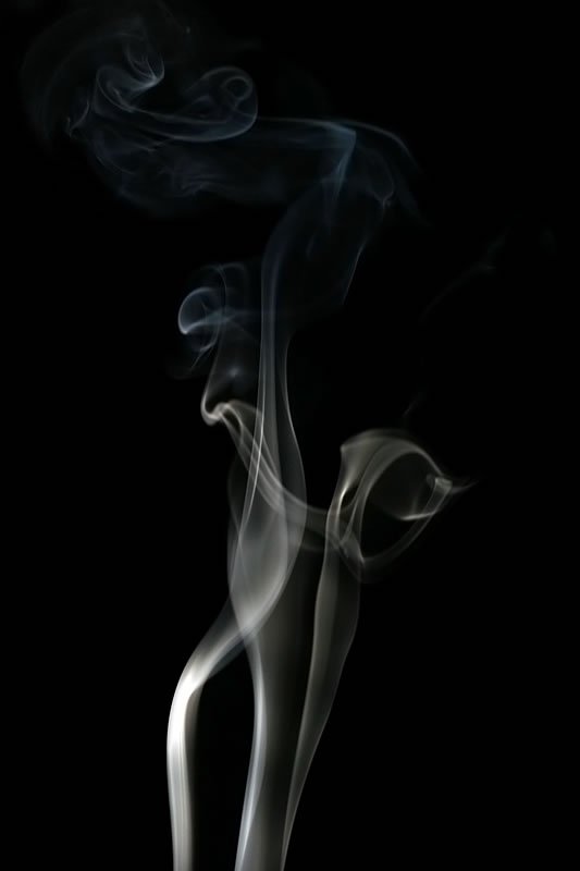 Delicate wisps of smoke curling against a black background.