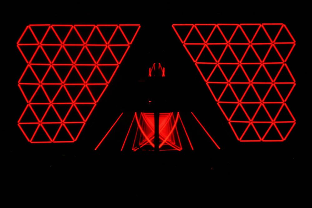 Abstract pattern of red neon triangles against a black background, showcasing intricate geometric designs.