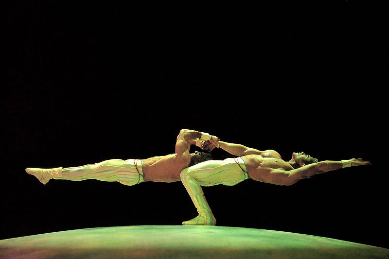 This image showcases a striking silhouette of nude female dancers performing an elegant pose. The composition highlights their graceful forms against a dark background.