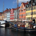 Kastellet Vibrant boats docked along a canal with colorful buildings in the background under a clear blue sky.