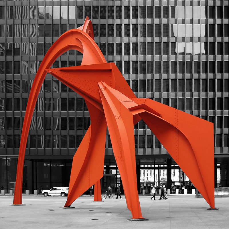 Exploring vibrant orange sculptures in a monochrome urban setting.