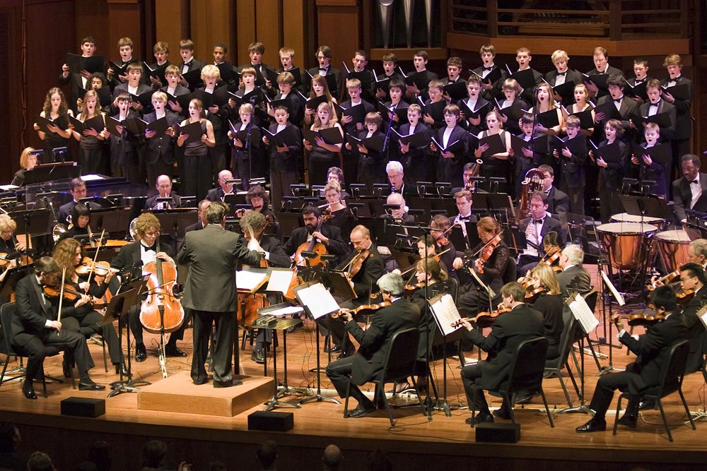 A symphony orchestra and choir are performing on a grand stage.