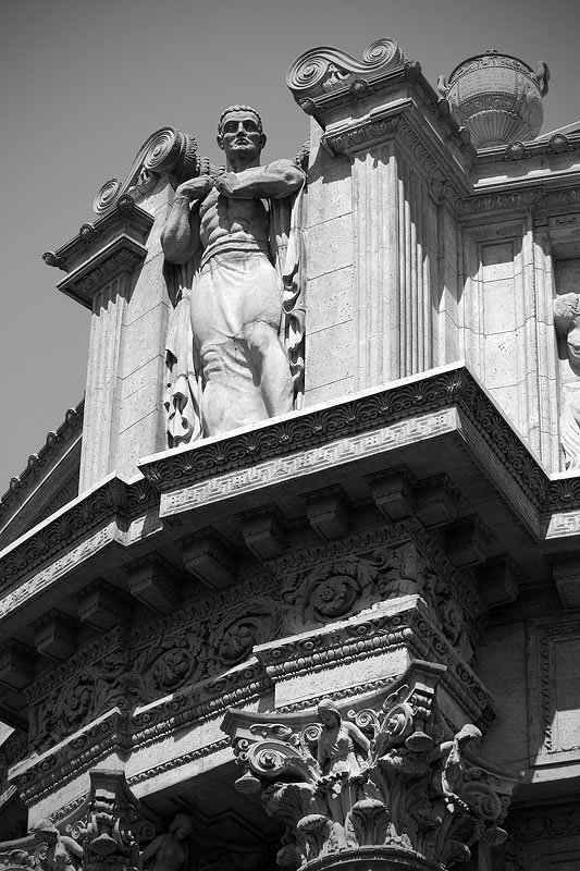 Classical statues grace the ornate columns and cornices of a grand government building, showcasing detailed architectural artistry.
