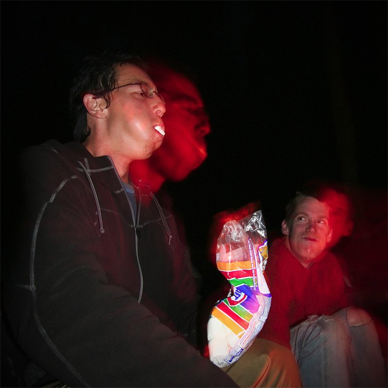 A couple from John and Kristie's photo blog relaxing outdoors at night. One person is holding colorful toe socks with a playful expression.