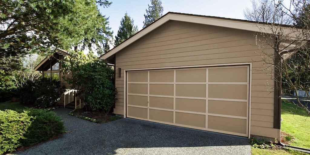 A beige garage with a large door, nestled among vibrant green bushes and trees, in a serene Pacific Northwest setting.