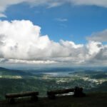 Lake 22 A panoramic view from a hilltop overlooking the Pacific Northwest landscape with benches in the foreground.
