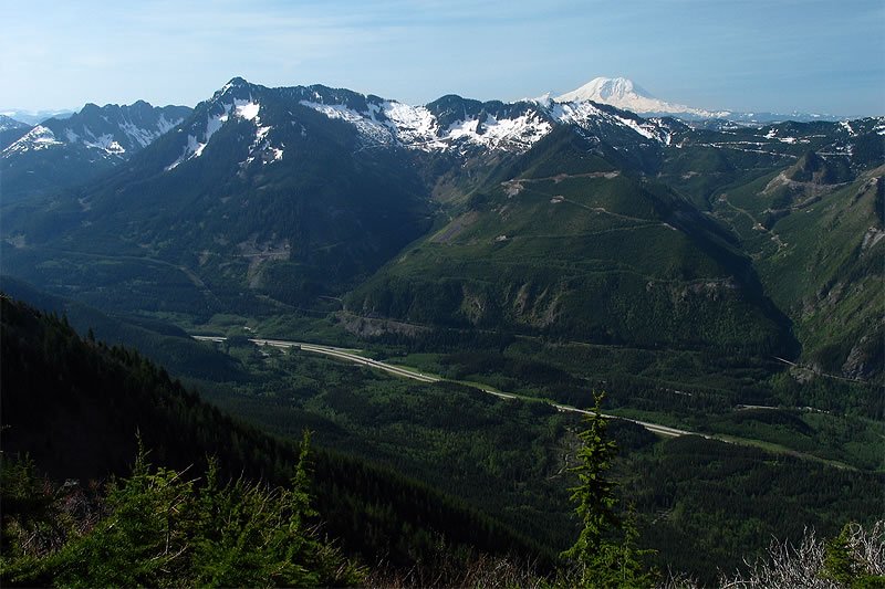 A breathtaking view of snow-capped mountains and lush green valleys in the Pacific Northwest.