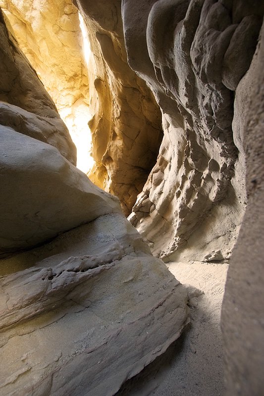 John and Kristie navigate through a sunlit cave passage on Palomar Mountain, showcasing its unique rock formations.