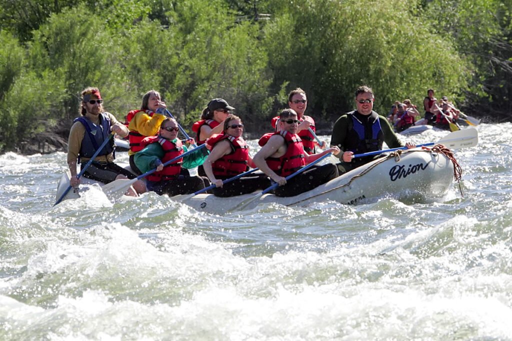 A group of people enjoying a rafting adventure, navigating through rough river rapids with paddles in hand.