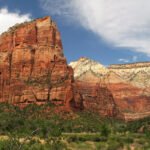 Bryce Canyon Majestic red rock cliffs rise against a bright blue sky with scattered clouds.