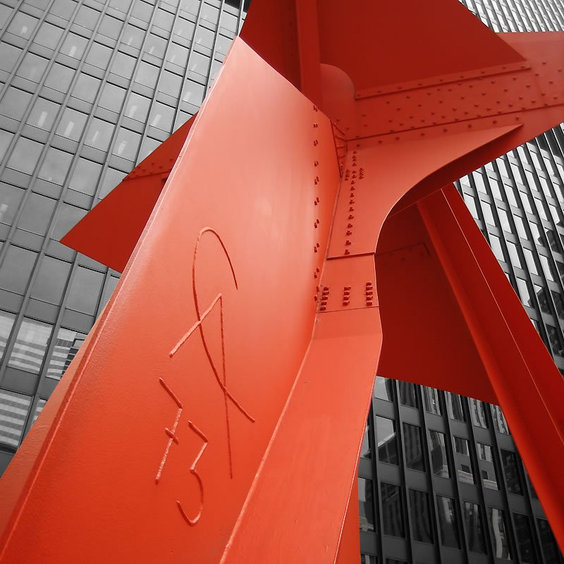 A vibrant red angle of Portland's iconic St. Johns Bridge, with the city's skyscrapers softly blurred in the background.