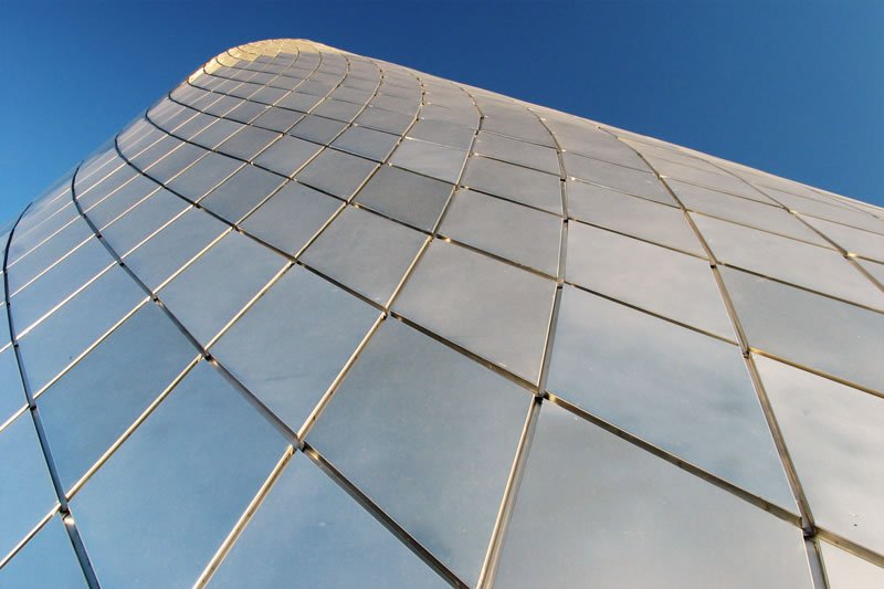 A modern glass skyscraper reflecting the sky, showcasing sleek architectural design.