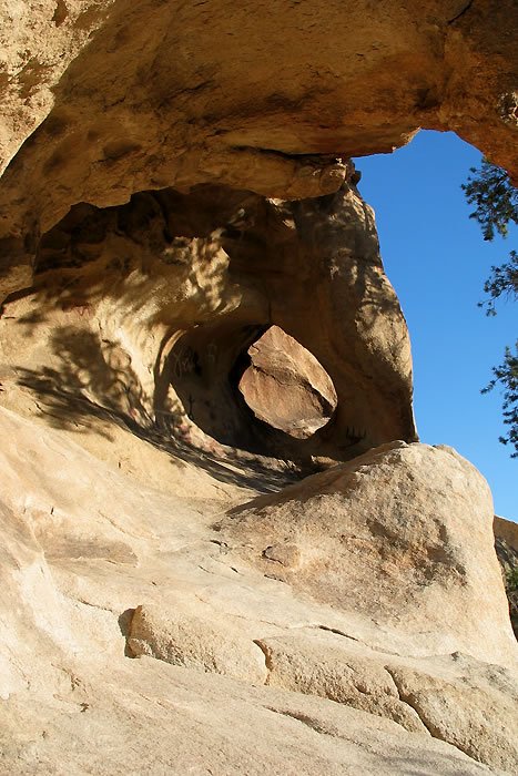 A natural rock arch with a clear blue sky. The scene captures the serene beauty of nature.