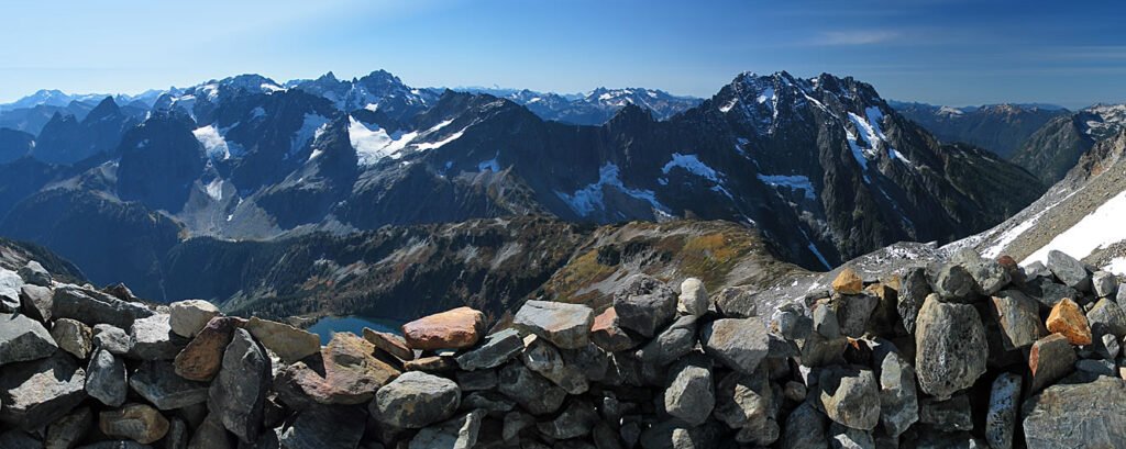 A scenic rock viewpoint overlooking a picturesque mountain range with clear blue skies.