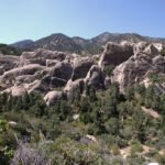 Ladder Canyon A panoramic view of jagged mountain peaks and lush forests under a clear blue sky.