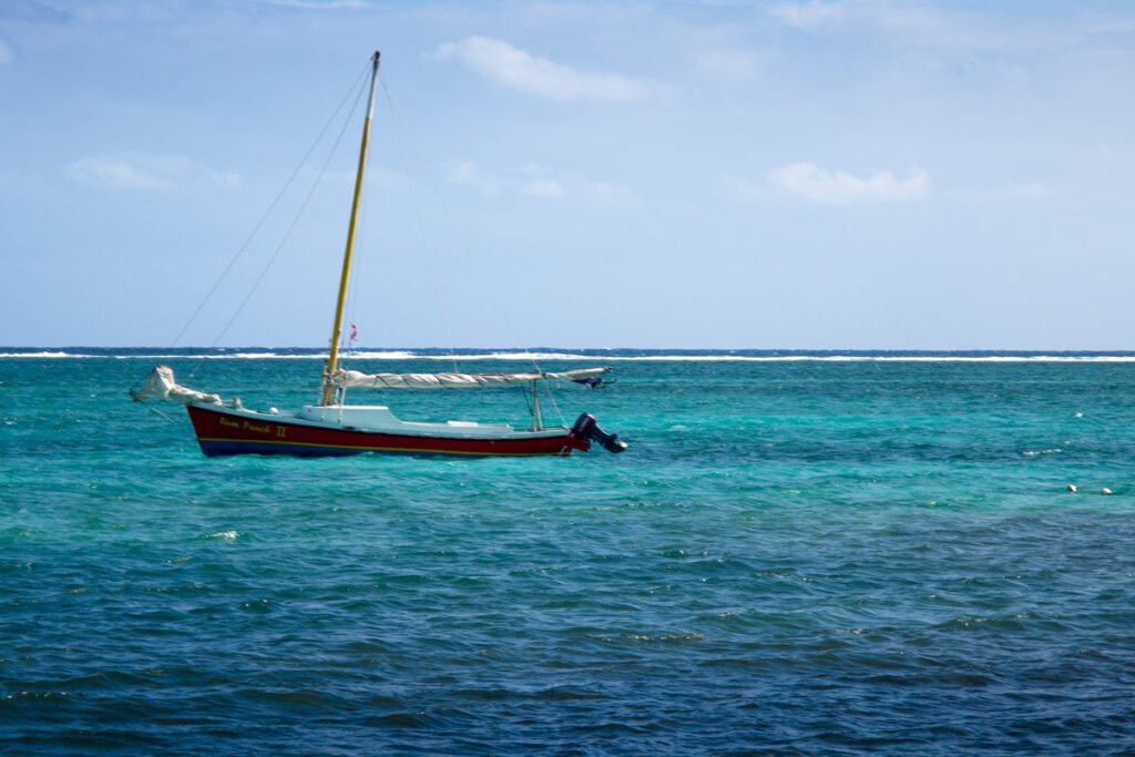 A vibrant sailboat gently bobbing in the serene, turquoise waters under a clear blue sky.