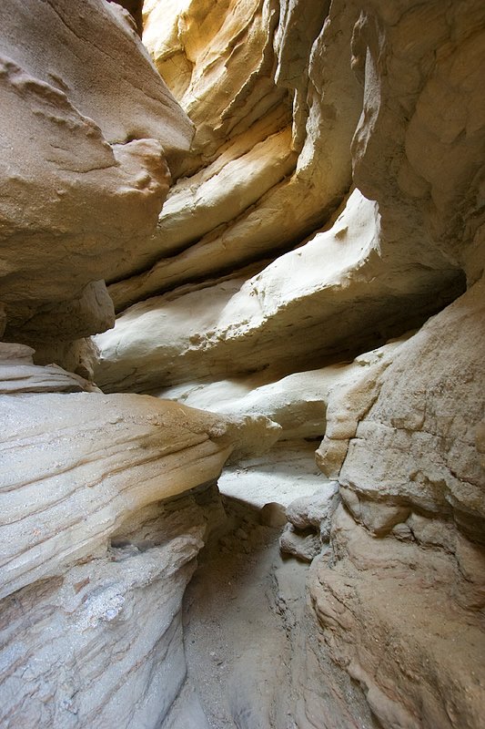 A view inside a narrow slot canyon with tall, curved rock walls.