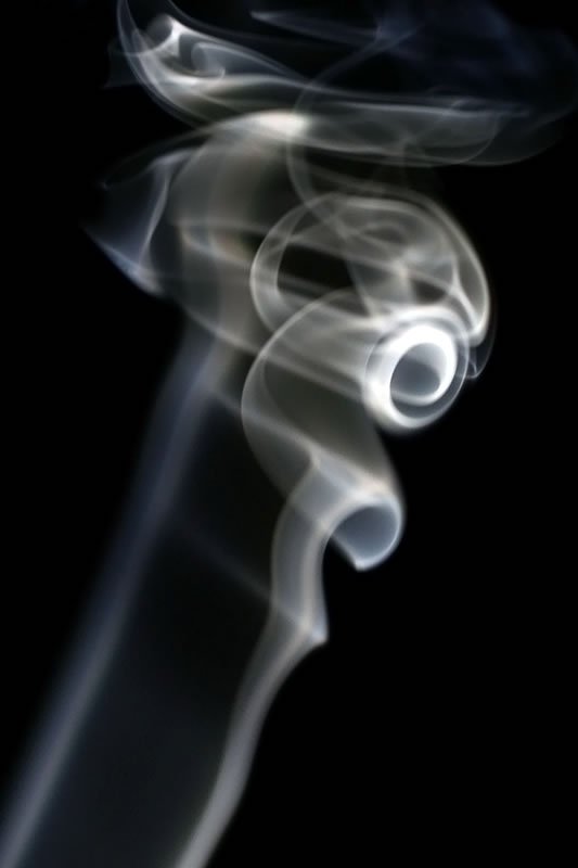 White smoke forms intricate patterns against a dark background, creating a mesmerizing visual effect.