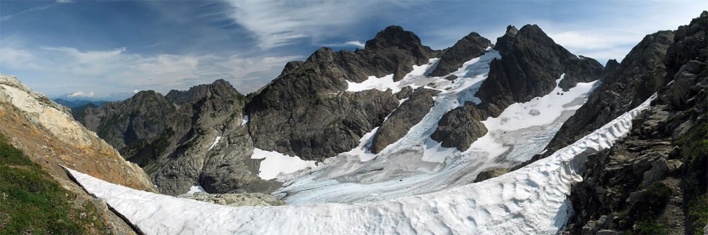 A stunning view of snow-covered mountains and a glacier. The rugged terrain showcases the majestic beauty of nature.