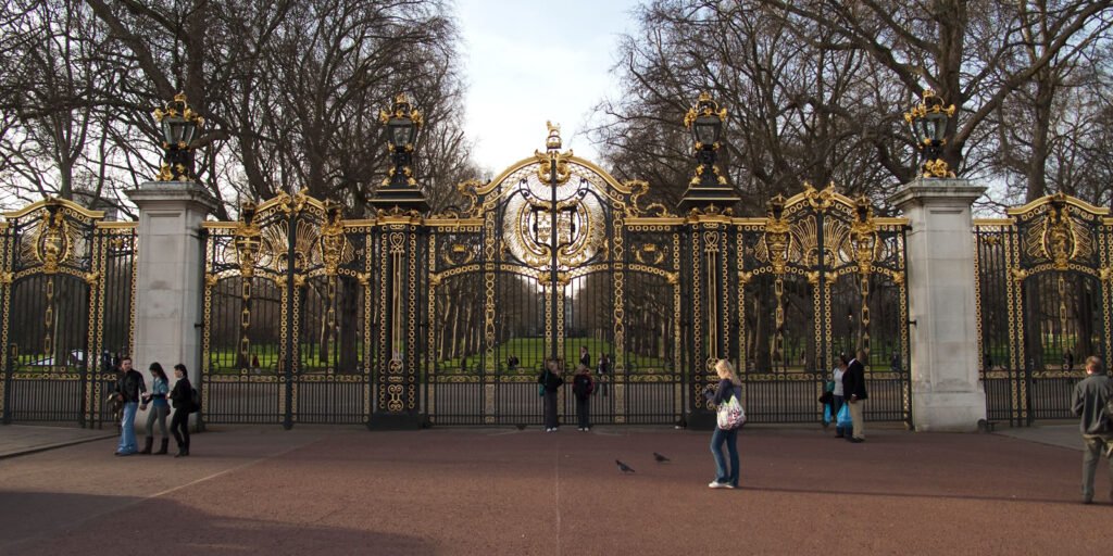 Golden gates of St. James's Park in London, UK. Visitors are seen near the entrance.