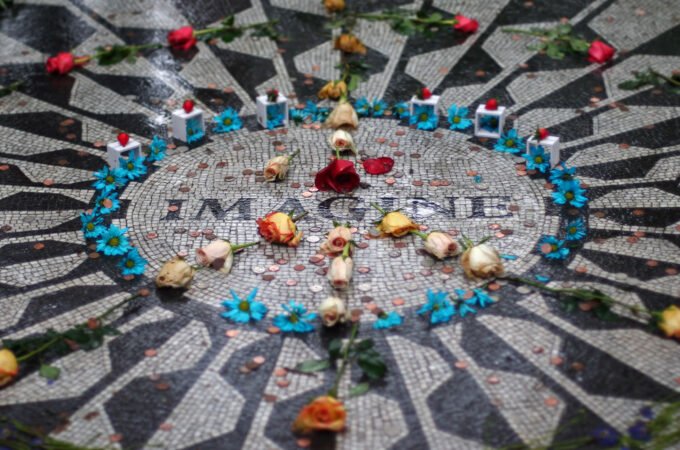 A close-up of the 'Imagine' mosaic in Central Park adorned with flowers and candles as a tribute.
