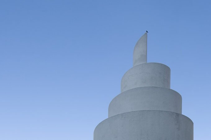 A close-up view of a white stupa tower against a clear blue sky, showcasing its unique architectural details.