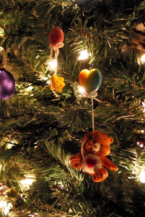 A close-up of a Christmas tree featuring a teddy bear ornament holding a balloon, surrounded by warm holiday lights.