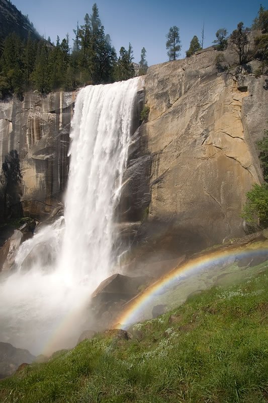Vernal Falls cascading down the cliff in Yosemite with a rainbow arching through the mist.