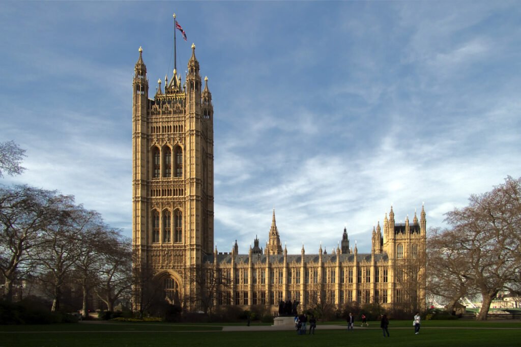 A stunning view of the Victoria Tower and Westminster Palace with blue skies above and green lawns below.