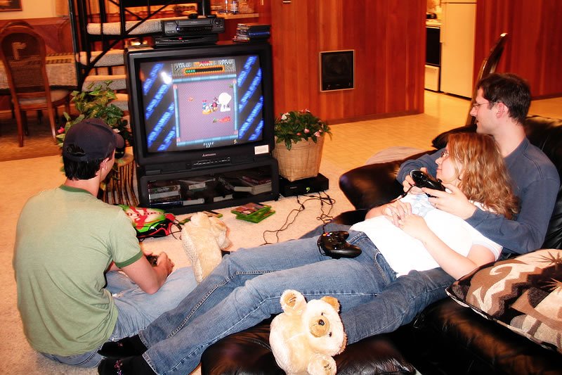 John and Kristie lounging on a couch playing a classic video game.