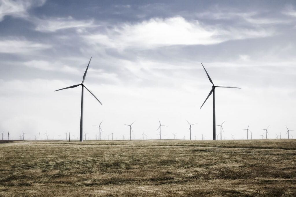 A landscape with wind turbines stretching across a field under a cloudy sky.