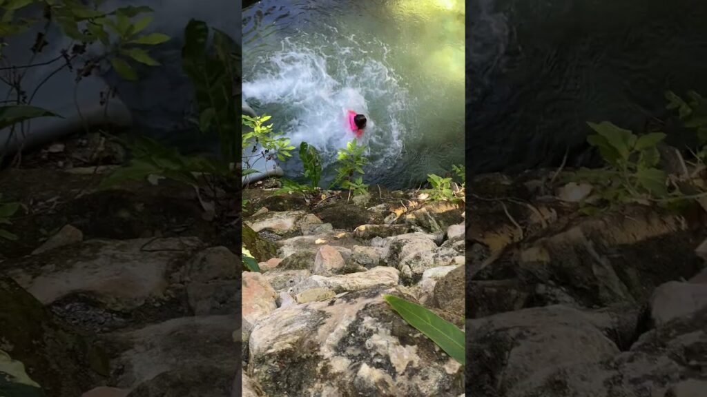 A splash of water above a rugged, stone-paved riverbank with green foliage.