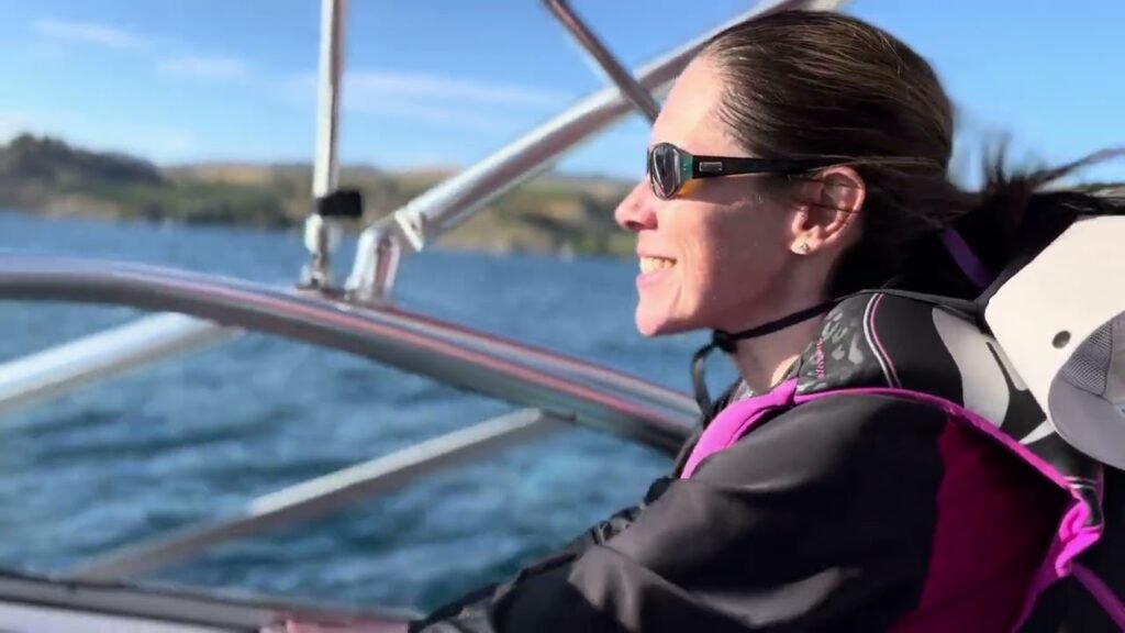 A person sailing on a boat in the Pacific Northwest, enjoying the scenic coastal views under a sunny sky.