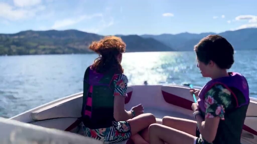 Two individuals enjoying a boat ride on a scenic lake with mountains in the background.
