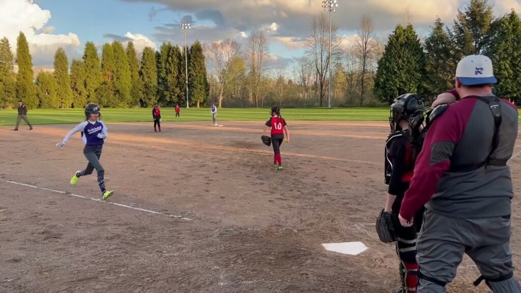 A baseball game being played on a dirt field with trees in the background.