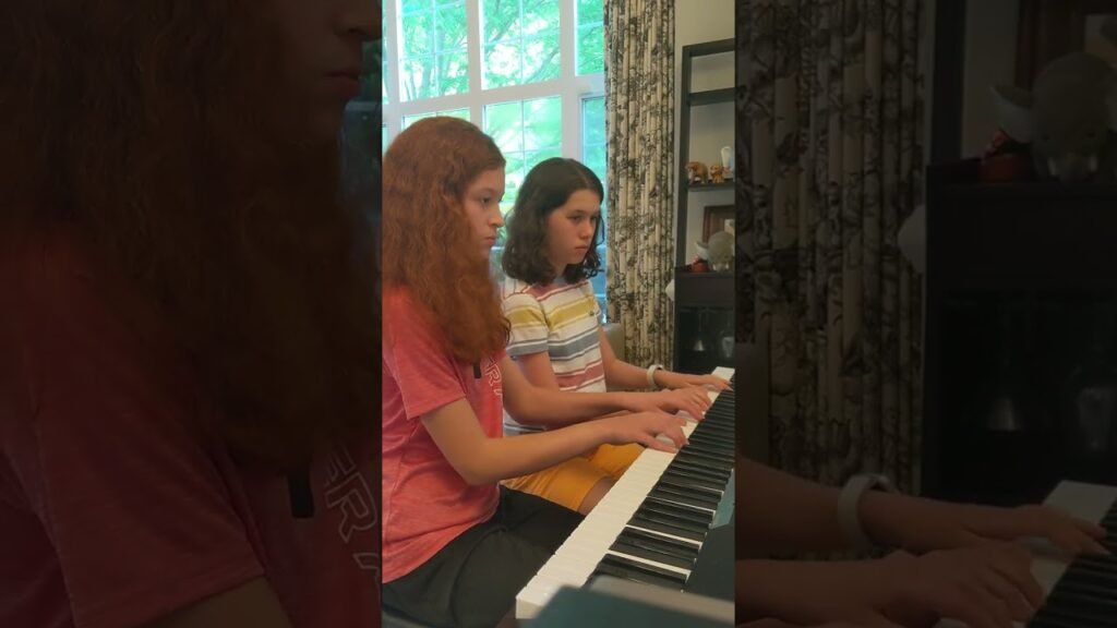Two individuals playing an electronic keyboard in a cozy indoor setting.