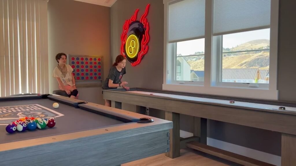 A cozy game room featuring a custom pool table and shuffleboard with a scenic Pacific Northwest view.