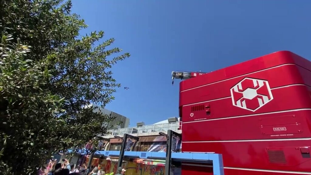 A bright red shipping container with a white hexagonal hexagon logo stands against a clear blue sky.