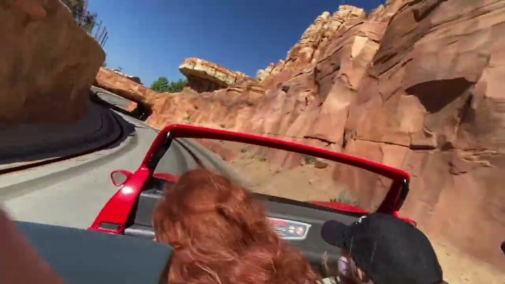 Traversing a rugged natural corridor with towering red rock formations overhead.