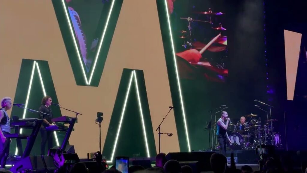 A wide shot of a concert stage showing musicians performing on illuminated letter structures.