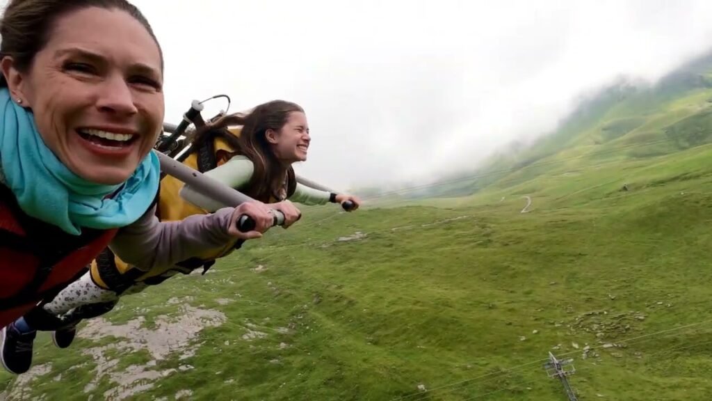 A two-person wingsuit flying session over misty green hills in the Pacific Northwest. An action shot taken on a foggy day above the mountains.